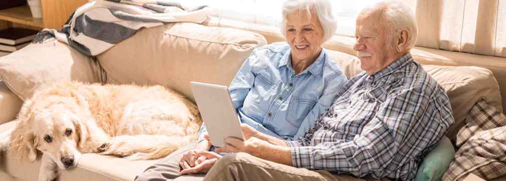 Elderly couple sitting on couch with their dog.