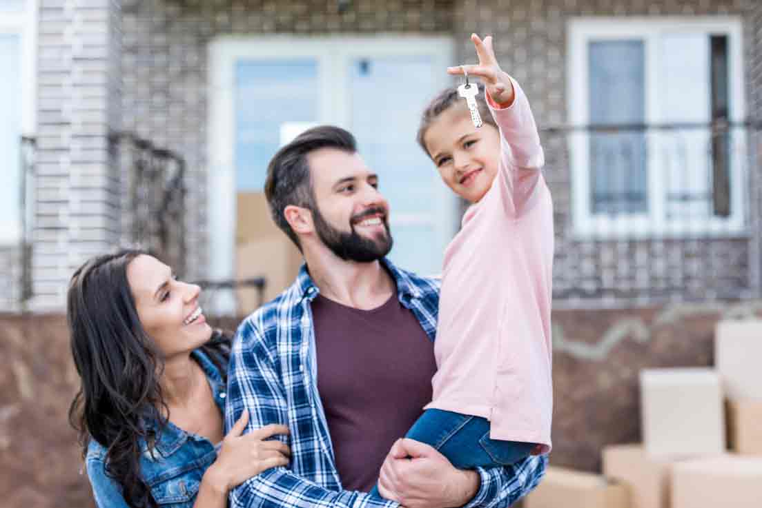 A young couple and child with keys to new home.